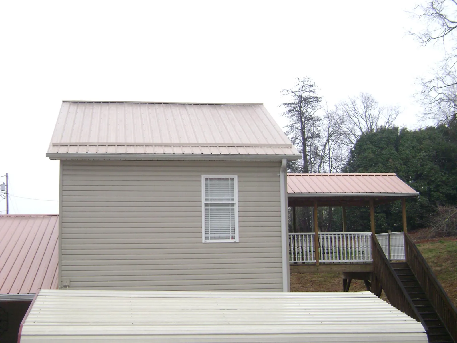Tan metal roofs on a two story addition and attached porch, from a Roof Replacement job in Mooresville